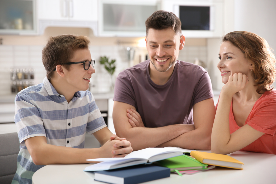 Teenager with Parents Doing Homework at Home